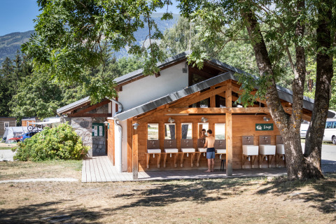 Buitenwasruimte bij Huttopia Bourg-Saint-Maurice glamping in Savoie, omgeven door natuur en bomen.