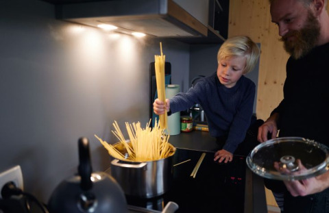 Barn og voksen laver mad sammen i et tiny house på Wellnester Camping bei Losheim am See, Saarland.