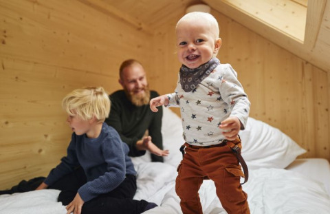 A family enjoys time in a cozy tiny house at Wellnester Camping near Losheim am See in Saarland.