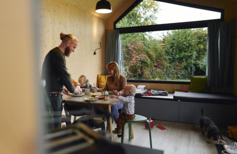 Famiglia che mangia in una tiny house accogliente del Wellnester Camping vicino a Losheim am See, Saarland.