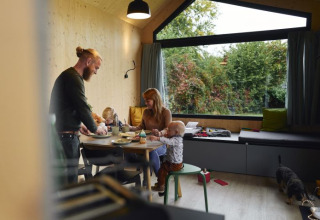 Famiglia che mangia in una tiny house accogliente del Wellnester Camping vicino a Losheim am See, Saarland.