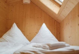 Indvendig udsigt over et glamping tiny house ved Wellnester Camping nær Losheim am See med trævægge og ovenlysvindue.