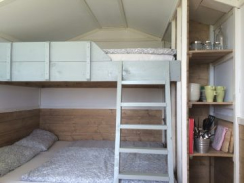 Interieur van glamping accommodatie met stapelbed, ladder en planken bij Agriturismo Camping Le Marche.