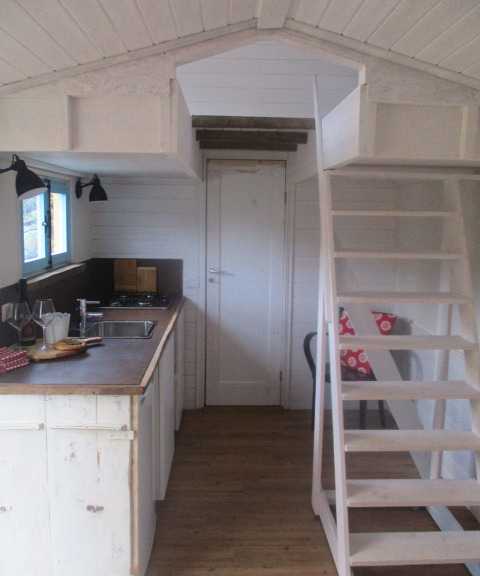 Interior de alojamiento glamping en Agriturismo Camping Le Marche, con cocina, entrepiso y escalera.