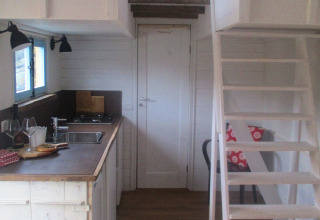 Interior de alojamiento glamping en Agriturismo Camping Le Marche, con cocina, entrepiso y escalera.