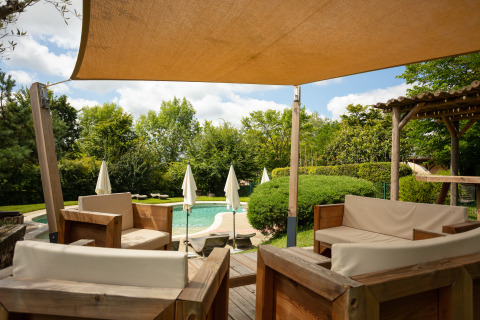 Udsigt over glampingområdets swimmingpool og træmøbleret terrasse på Camping Pré Fixe i Pyrenæerne.