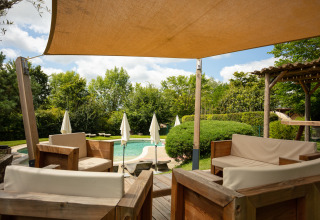 Udsigt over glampingområdets swimmingpool og træmøbleret terrasse på Camping Pré Fixe i Pyrenæerne.