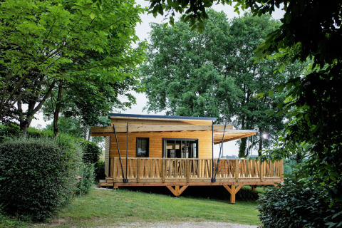 Glamping-Lodge auf Camping Pré Fixe, aus Holz gebaut, umgeben von Bäumen in den Pyrenäen.