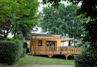 Wooden glamping lodge at Camping Pré Fixe, nestled among trees and lush greenery in the Pyrenees.