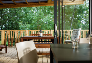 Lodge de glamping moderne avec terrasse en bois, table à manger et vue sur la forêt au Camping Pré Fixe, Pyrénées.