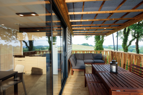 Overdækket terrasse med loungesofa og spisebord på glamping campingpladsen Camping Pré Fixe i Pyrenæerne.