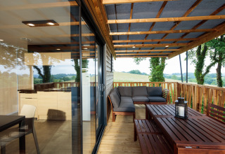 Terrazza coperta con divano da esterno e tavolo da pranzo al Camping Pré Fixe - Lodges nei Pirenei.