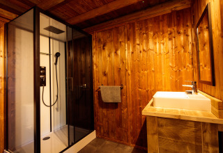 Salle de bain en bois avec douche moderne et lavabo, hébergement glamping Camping Pré Fixe dans les Pyrénées.