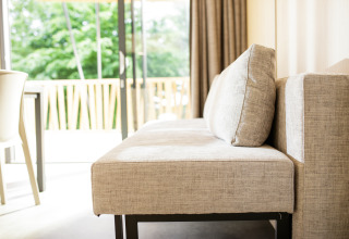 Moderne sofa ved vindue med udsigt til grønne træer i glamping indkvartering på Camping Pré Fixe i Pyrenæerne.