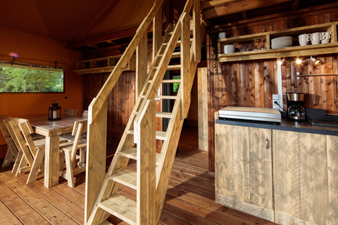 Landelijk houten interieur van een glamping lodge bij Camping Pré Fixe in de Pyreneeën met keuken en eethoek.