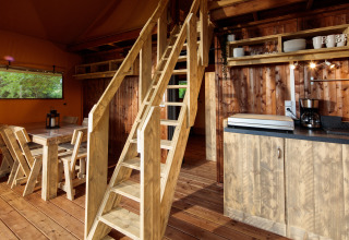 Interior rústico de madera en un lodge glamping en Camping Pré Fixe en los Pirineos, con cocina y comedor.