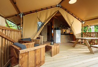 Glamping-Unterkunft mit Holzterrasse, Sitzgelegenheiten und Küche auf dem Camping Pré Fixe in den Pyrenäen.
