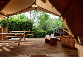 Wooden terrace with picnic table and lounge area at Camping Pré Fixe glamping lodge in the Pyrenees.
