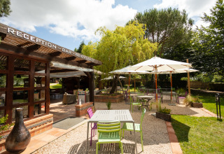Terrazza esterna con sedie colorate e ombrelloni al Camping Pré Fixe Lodges nei Pirenei francesi.