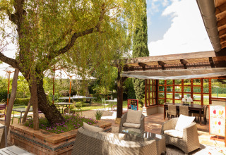 Zona de descanso al aire libre en Camping Pré Fixe - Lodges en los Pirineos con muebles y vegetación.