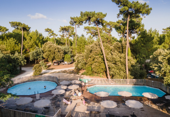 Zwembaden en ontspanning bij Huttopia Oléron les Pins Glamping, omringd door pijnbomen in Nouvelle-Aquitaine.