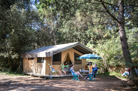 Familia disfruta de glamping en Huttopia Oléron les Pins, Nouvelle-Aquitaine, afuera de una tienda de lujo.