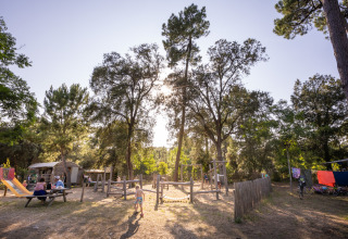 Niños jugando en el parque al aire libre de Huttopia Oléron les Pins, glamping en Nouvelle-Aquitaine.
