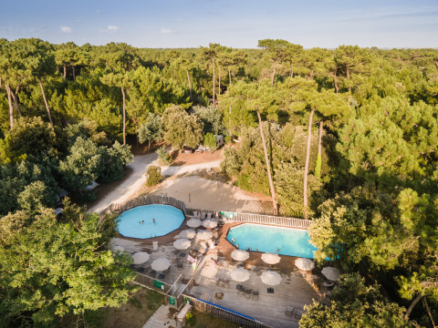 Veduta aerea del glamping Huttopia Oléron les Pins in Nouvelle-Aquitaine, con piscine tra pini e ombrelloni.
