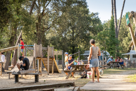 Familias se divierten al aire libre en área de juegos y picnic del glamping Huttopia Oléron les Pins.