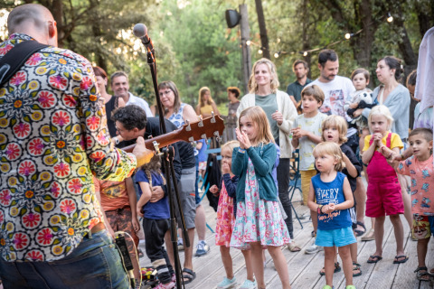 Kinder und Erwachsene genießen Live-Musik im Freien auf dem Glampingplatz Huttopia Oléron les Pins.