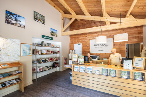Accueil du Huttopia Oléron les Pins avec équipe, brochures et décoration en bois, ambiance conviviale.