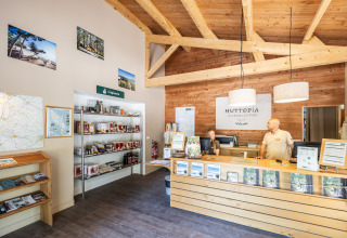 Recepción de Huttopia Oléron les Pins, personal atendiendo, decoración de madera e información turística.