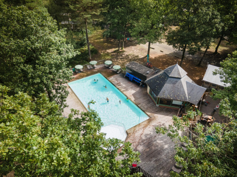 Luftfoto af Huttopia Lac de Sillé glamping i Pays de la Loire med pool omgivet af træer og terrasser.