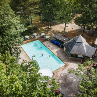 Luftfoto af Huttopia Lac de Sillé glamping i Pays de la Loire med pool omgivet af træer og terrasser.
