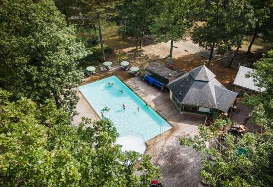 Vista aerea di Huttopia Lac de Sillé - Glamping Pays de la Loire con piscina e terrazza in legno.