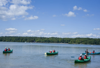 Ospiti remano in canoa sul lago di Huttopia Lac de Sillé - Glamping Pays de la Loire in una giornata di sole.