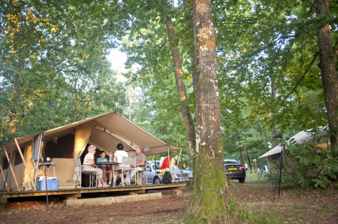 Gezin geniet van glamping bij Huttopia Lac de Sillé in Pays de la Loire, omringd door bos.