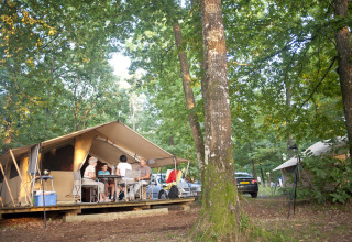 Gezin geniet van glamping bij Huttopia Lac de Sillé in Pays de la Loire, omringd door bos.