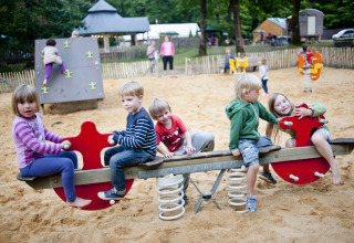 Kinder spielen auf einer Wippe im Sandspielplatz bei Huttopia Lac de Sillé - Glamping Pays de la Loire.