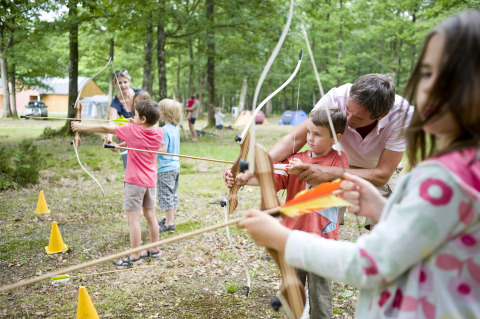 Children practice archery outdoors at Huttopia Lac de Sillé - Glamping Pays de la Loire, glamping campground.
