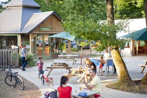 Udendørs opholdsområde ved Huttopia Lac de Sillé glamping i Pays de la Loire med borde og legeplads.