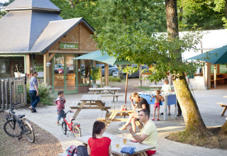 Outdoor seating area at Huttopia Lac de Sillé glamping in Pays de la Loire with picnic tables and families.