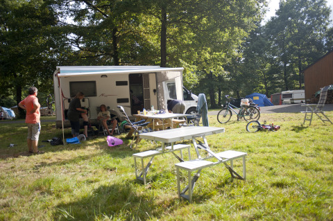 Famiglia in campeggio a Huttopia Lac de Sillé - Glamping Pays de la Loire con caravan e area picnic.