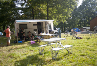 Gezin bij Huttopia Lac de Sillé - Glamping Pays de la Loire met caravan en picknicktafel in het groen.