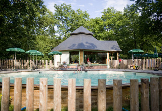 Swimmingpool og afslapningsområde ved glampingpladsen Huttopia Lac de Sillé i Pays de la Loire, omgivet af natur.