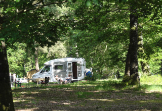 Campingplads med autocamper og gæster under træerne ved Huttopia Lac de Sillé - Glamping Pays de la Loire.