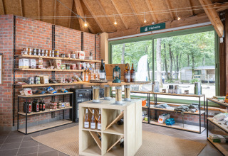 Tienda con productos locales y vino en Huttopia Lac de Sillé - Glamping Pays de la Loire, vista hacia la naturaleza.