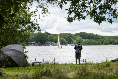 Fisker i naturen ved søen med telt, glamping ved Huttopia Lac de Sillé, Pays de la Loire, Frankrig.