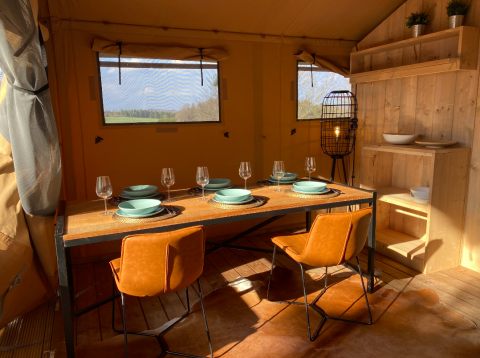 Interior of glamping tent at Azur Camping Altmühle, Nature Lodge Bavaria, with dining table and tableware.