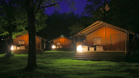 Beleuchtete Glamping-Zelte im Azur Camping Altmühle (Kipfenberg) Nature Lodge Beieren bei Nacht im Grünen.